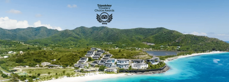 Aerial view of a beach side resort surrounded by greenery and blue waters with a logo of Tripadvisor Travelers' Choice Awards 20225 on the top | Tamarind Hills Resort and Villas - Antigua